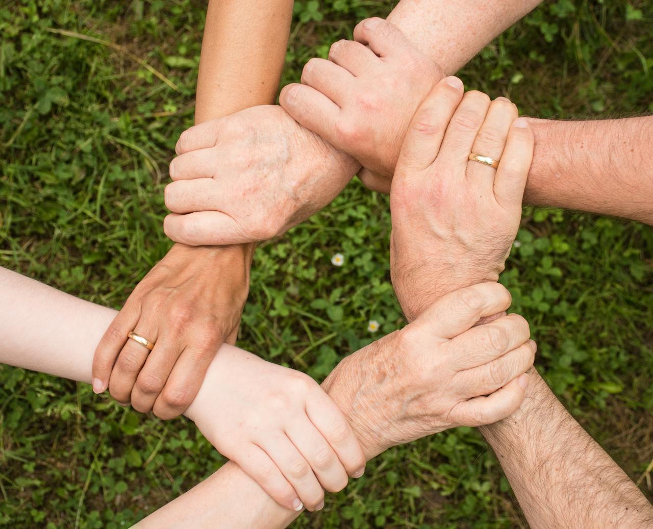 why-choose-us Close-up of diverse hands forming a connection, symbolizing teamwork and unity outdoors.
